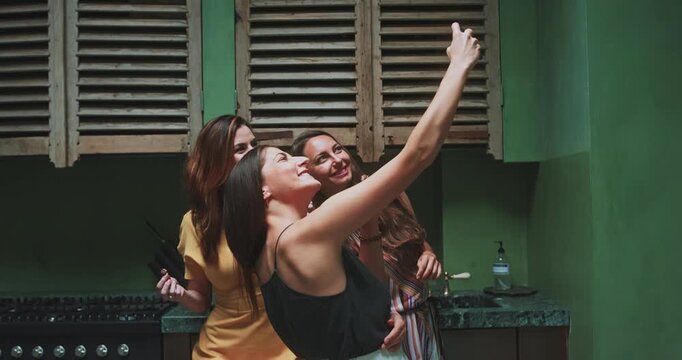 Three beautiful women taking selfie together in studio kitchen