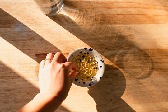 A person holding a vitamin D tablet in the sunlight