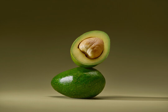 A halved avocado balancing on top of a whole one