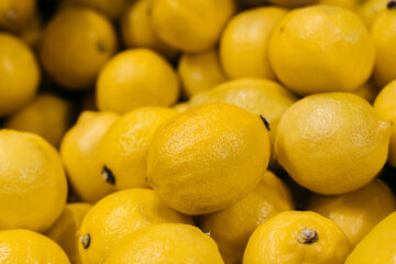 Fresh yellow lemons piled together, showcasing their vibrant color and textured skin, representing natural produce and healthy lifestyle choices in a market setting