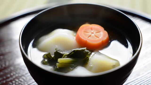 Steaming Bowl of Traditional Japanese New Years Zoni Soup with Mochi and Decorative Carrot.