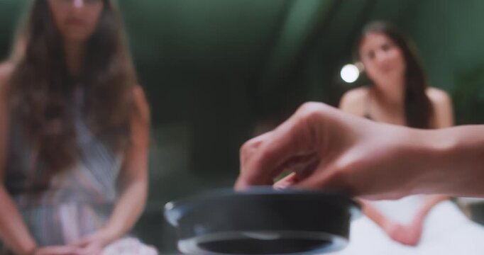 Hand placing teapot lid during tea gathering, close-up