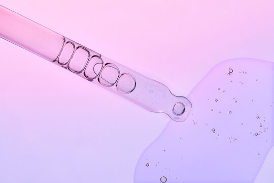 Clear Glass Pipette with Drop of Liquid on Gradient backdrop.