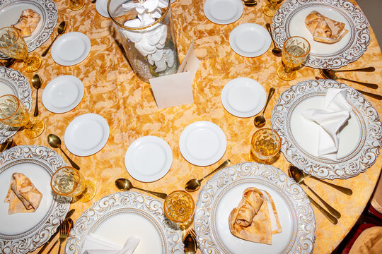Celebration table featuring shiny utensils, plates, and golden decor