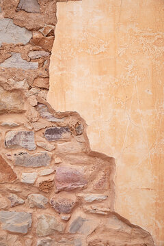 A weathered stone wall with stucco reveals an aged, textured surface.