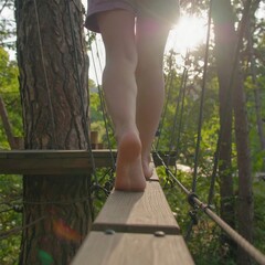 Barefoot person walks a high wooden plank