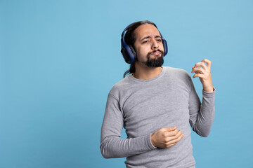 Fototapeta premium Relaxed person enjoying music on headphones expressing joy for leisure activity. Modern adult showcases enjoyment of audio entertainment and wireless gadgets in a professional studio.