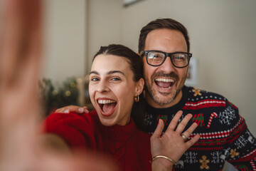 Happy couple taking christmas self portrait wearing holiday sweaters