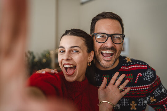 Happy couple taking christmas self portrait wearing holiday sweaters