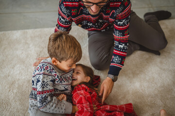 Father and children tickling and laughing on christmas morning