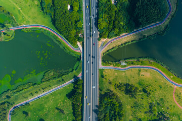 Aerial View of Highway Overpass Crossing Green Park and Lakes