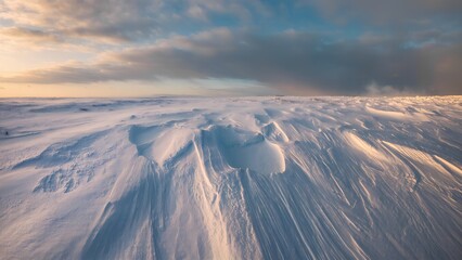 Wind-sculpted snow dunes in soft sunset light, abstract natural winter landscape with copy space