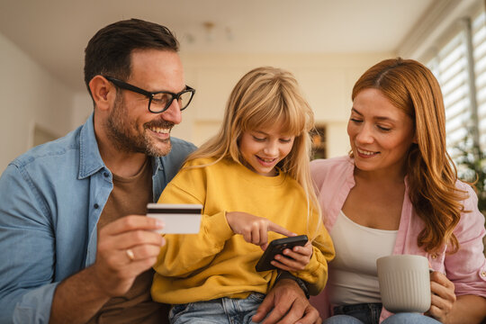 Happy family making online payment using credit card and smart phone - Powered by Adobe