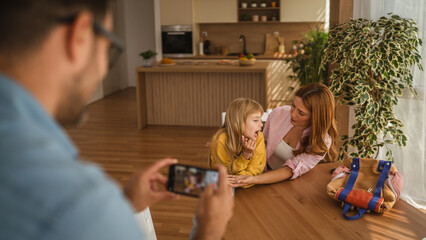 Father taking photo of his daughter and wife at home