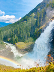 Krimml, Austria - 08-06-2025 : Wide shot of a waterfall flowing down between the forest at the  Krimml Waterfalls.