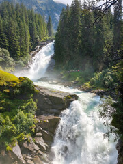 Krimml, Austria - 08-06-2025 : Wide shot of two waterfalls flowing between the trees at the  Krimml Waterfalls.