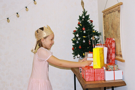 Girl is looking for her present under Christmas tree.