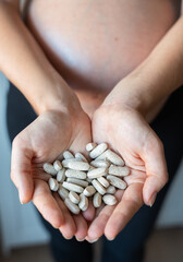 Pregnant woman holding prenatal vitamins in hands: ensuring healthy pregnancy
