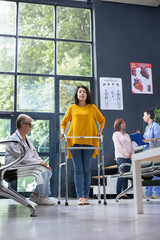 Medic assisting asian woman for her physical therapy with walking frame during rehabilitation at the hospital lobby, checkup visit appointment. Healing process for a person with mobility issues.