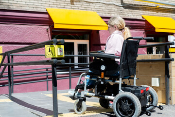 Young faceless woman on a motorized wheelchair rides on a ramp
