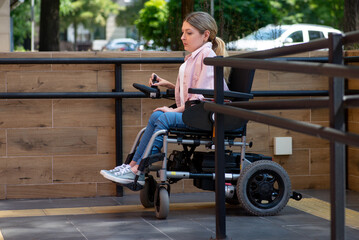 Young woman on a motorized electric wheelchair rides on a ramp