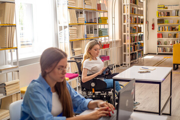 Disabled woman in wheelchair working on tablet in coworking space