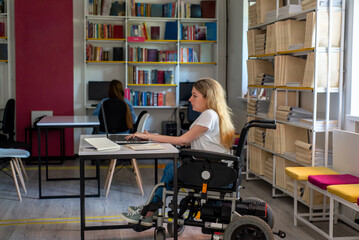 Disabled woman in wheelchair working on laptop in coworking space