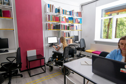 Woman in wheelchair works on PC next to colleague in inclusive office