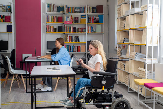 Disabled woman in wheelchair working on tablet in coworking space