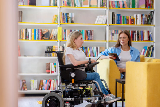 Woman in a wheelchair communicating with colleague in coworking space
