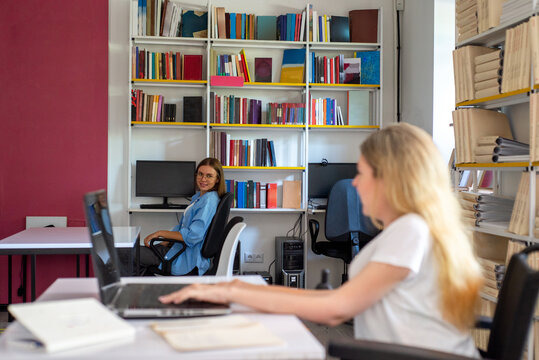 Two female employees chat in a office. Woman is in a wheelchair.