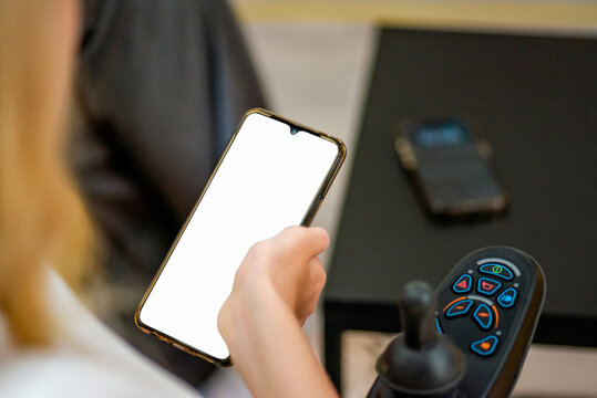 Young faceless woman in wheelchair using phone with blank screen