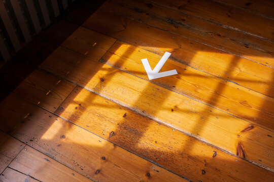 Pointing the way, a white arrow pointing direction on a wooden floor