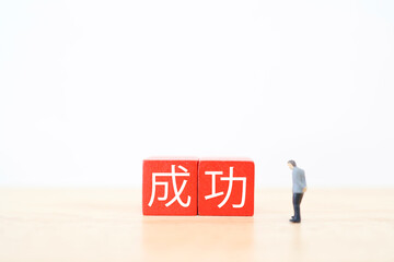 Naklejka premium 成功を見つめるミニチュアビジネスマンと赤いブロック