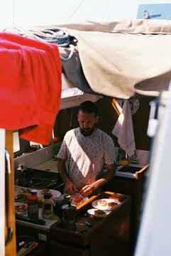 Man prepares food in a boat cabin
