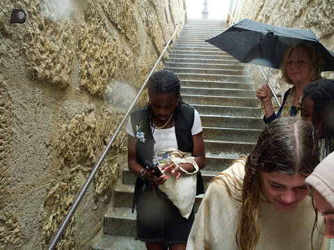 Group of Tourists Seeking Shelter From Rain on Ancient Stone Steps