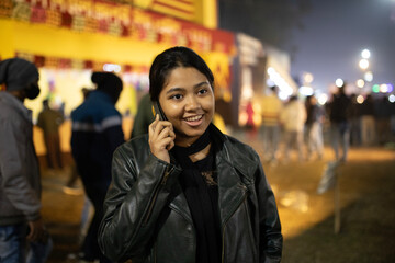 Young woman speaking with smartphone at nighttime in a crowded place