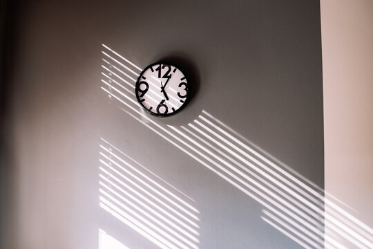 Wall clock casting shadows from window light