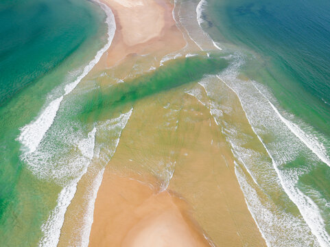 Waves either side of a sand isthmus cut by a tidal channel