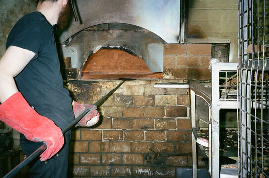 35mm Film Scene Of Man Preparing Brick Oven For Traditional Baking