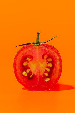 Halved cherry tomato on an orange background