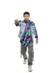 Fototapeta premium Stylish Asian man in denim jacket and cargo pants walks forward, pointing directly at the camera with a surprised expression. Urban fashion, youth culture, engagement.