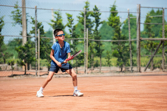 Young Boy Playing Tennis on Clay Court