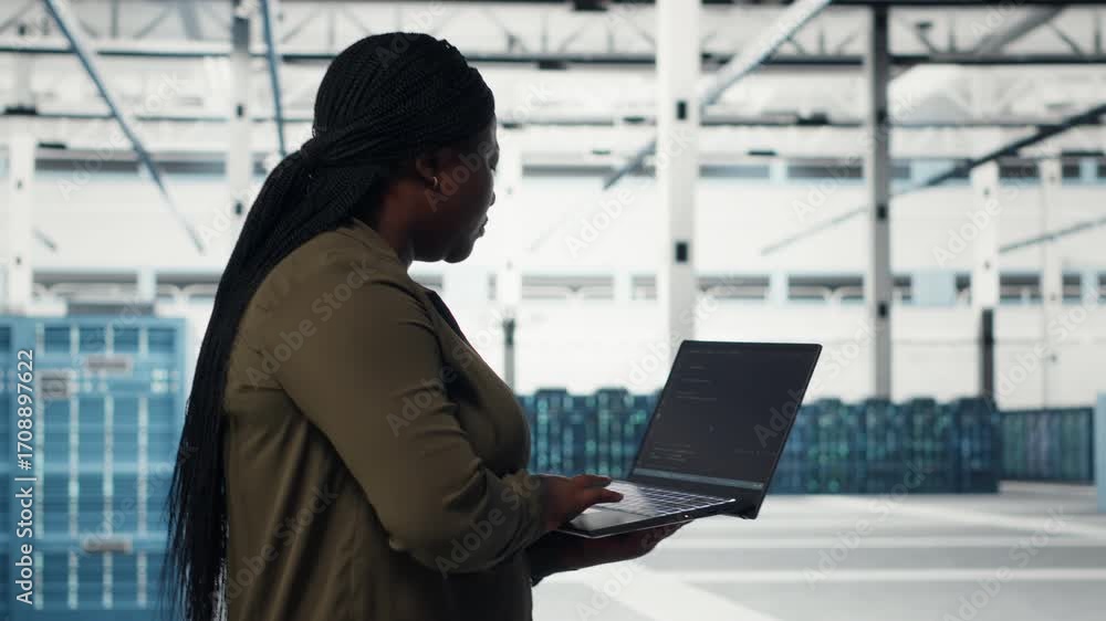 Poster technician with laptop walks through data center server rows, implementing advanced power management