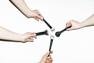 Hands holding various make up beauty brushes for different products 