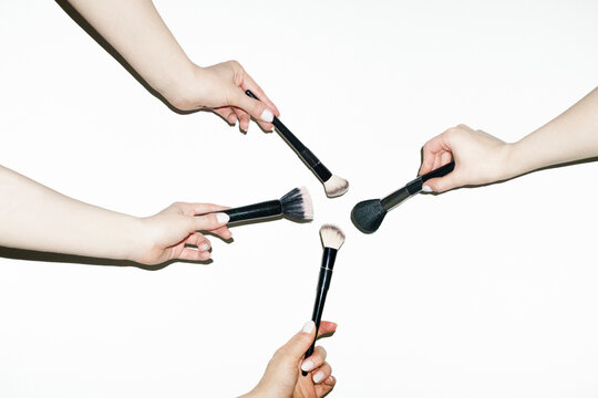 Hands holding various make up beauty brushes for different products 