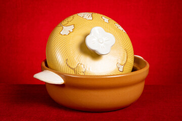 a rustic ceramic pot on red background