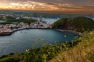 Fototapeta premium Faial, Azores, island, Portugal, Beautiful view of a bay with a boat in the water. The sky is orange and the water is calm
