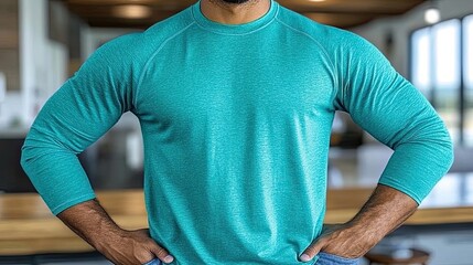 Muscular man posing confidently in teal long sleeve shirt indoors setting