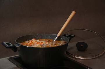 Delicious pilaf is being cooked in pot with spoon